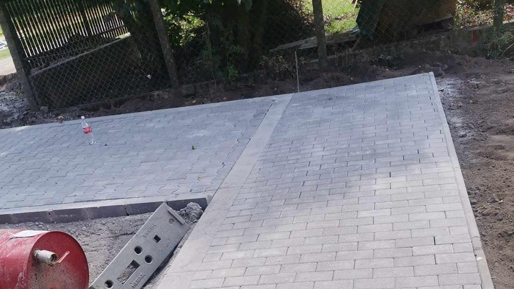 Ipari térkővezett udvar – lineáris folyókákkal, oszlopos előtetővel